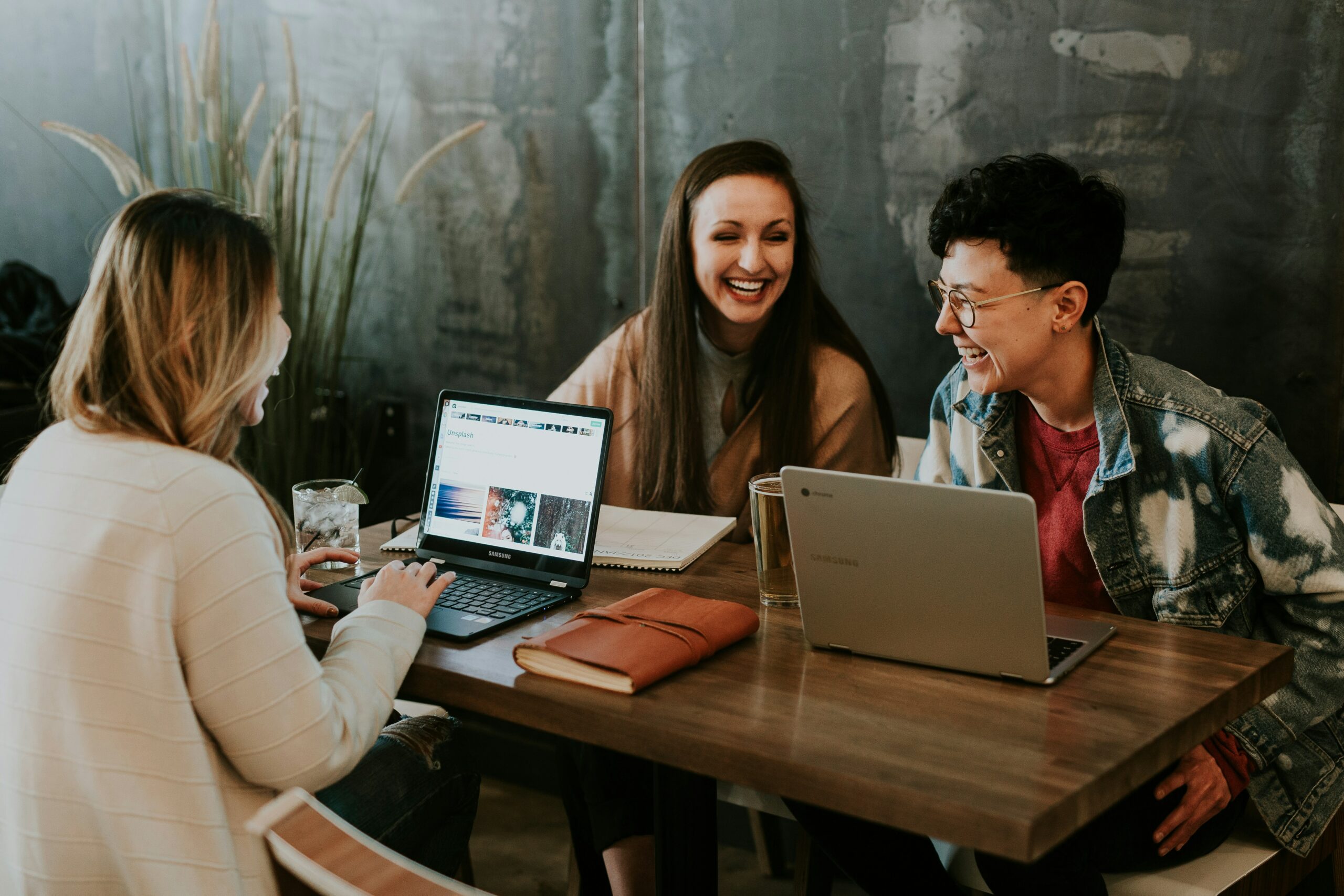 Three women at a table on computers.